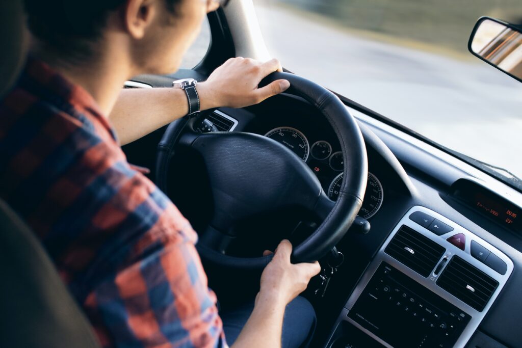 uomo di spalle che guida auto